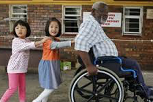 Children help man in wheelchair